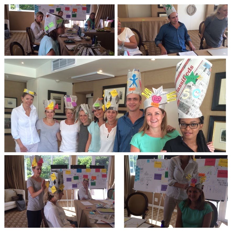 Team members playing with handmade thinking hats
