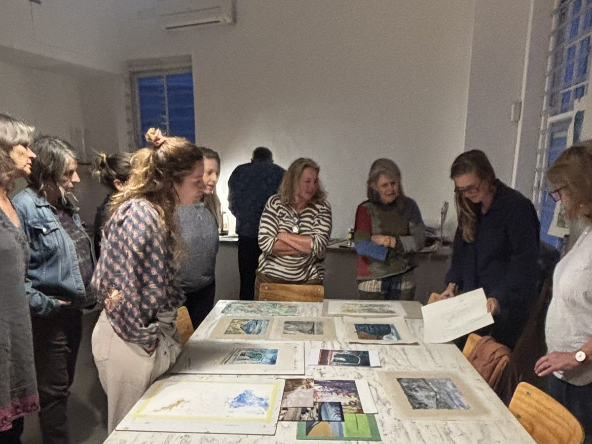 Art therapy group gathered around a table of artwork